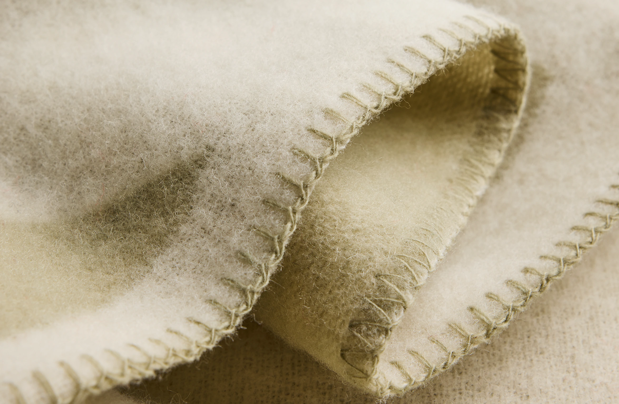 Merino wool blanket in sage green with an abstract pattern