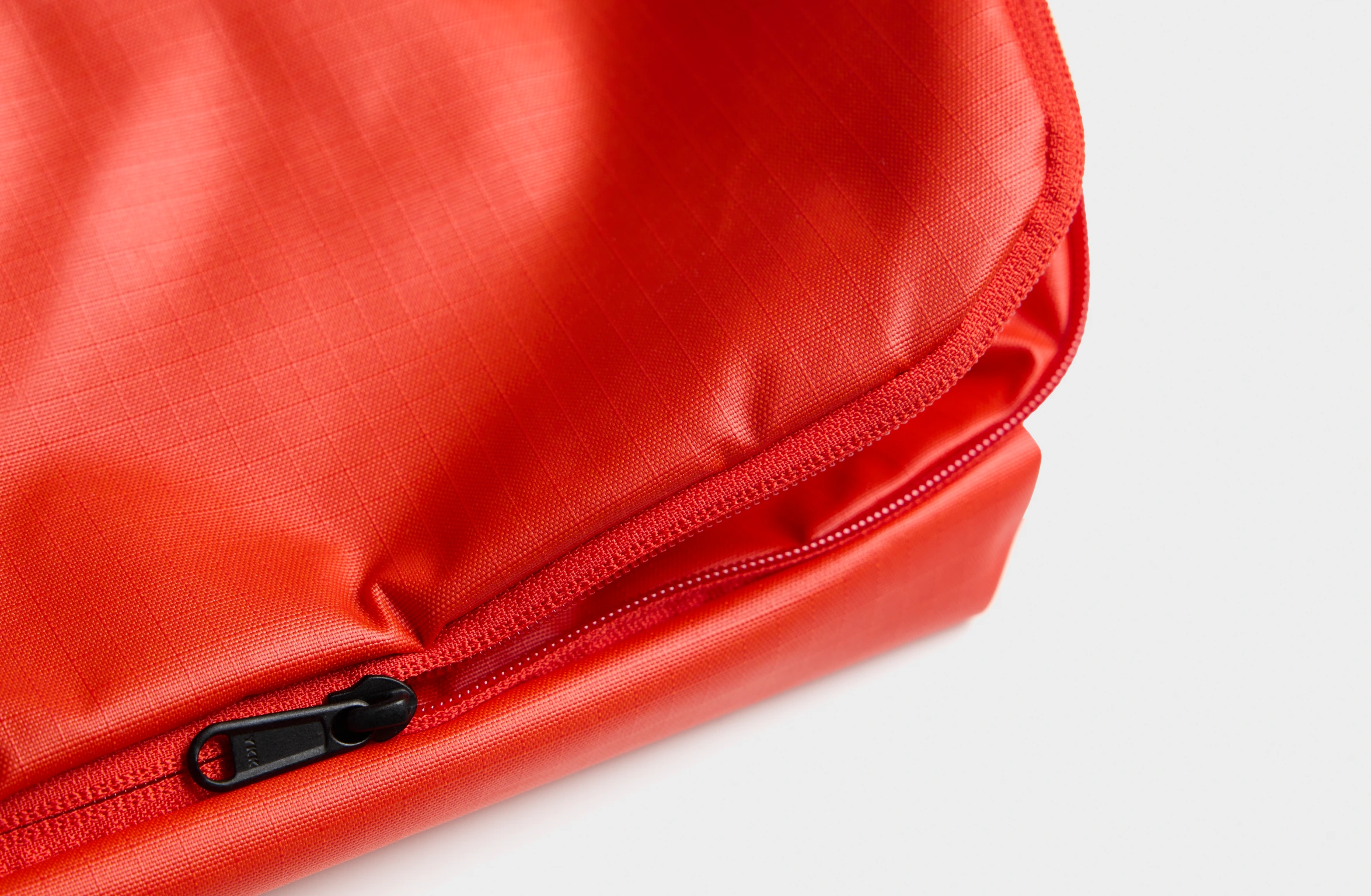 Rød sling bag med justerbar rem og et mærke på skulderpuden.