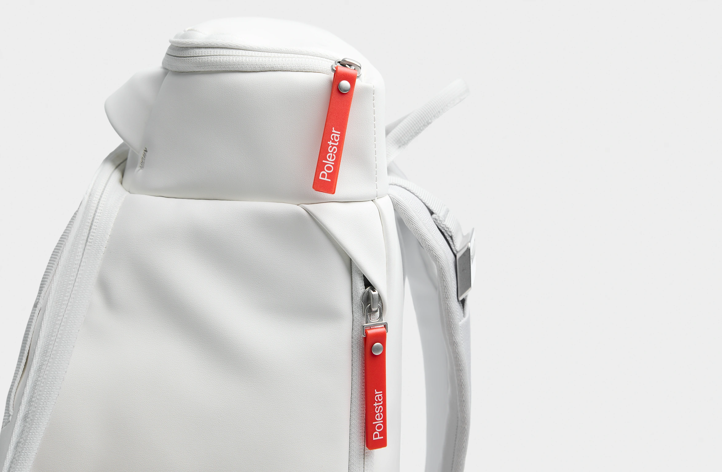 Weißer Rucksack mit orangefarbenen Details, gepolsterten Trägern und seitlich angebrachtem Branding von Polestar und Db
