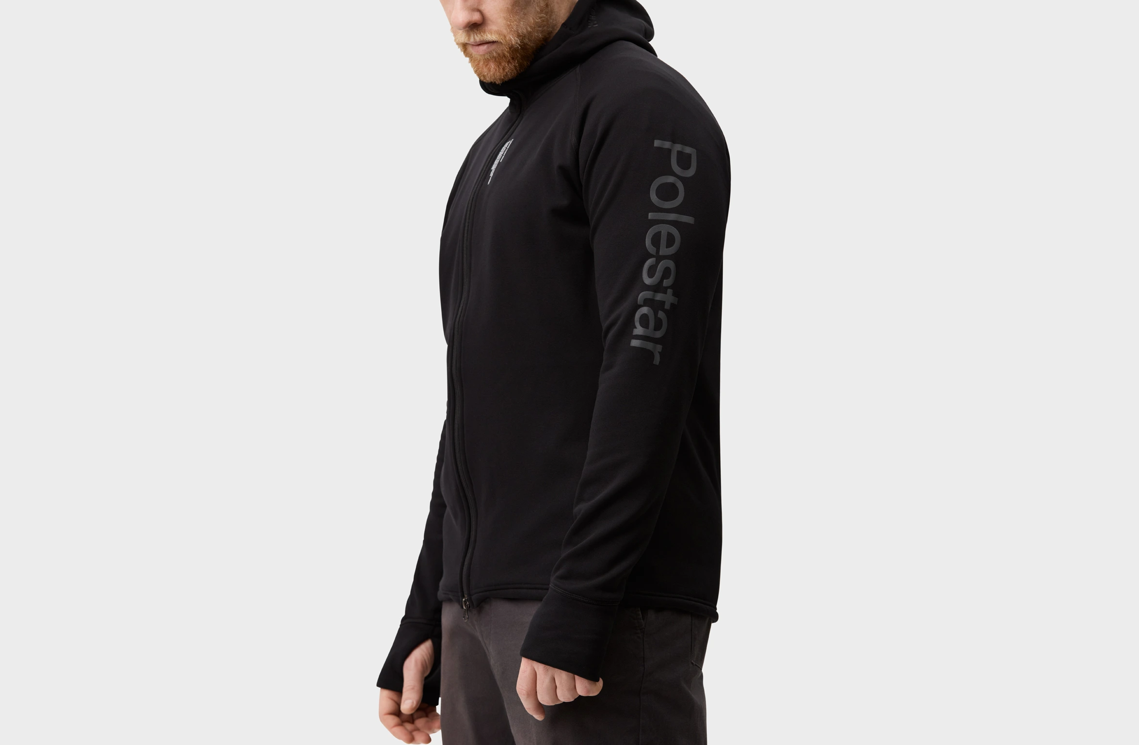 Zwarte hoodie met doorlopende ritssluiting, voorzien van Polestar-woordmerk op de linkermouw en Polestar-logo links op de achterkant