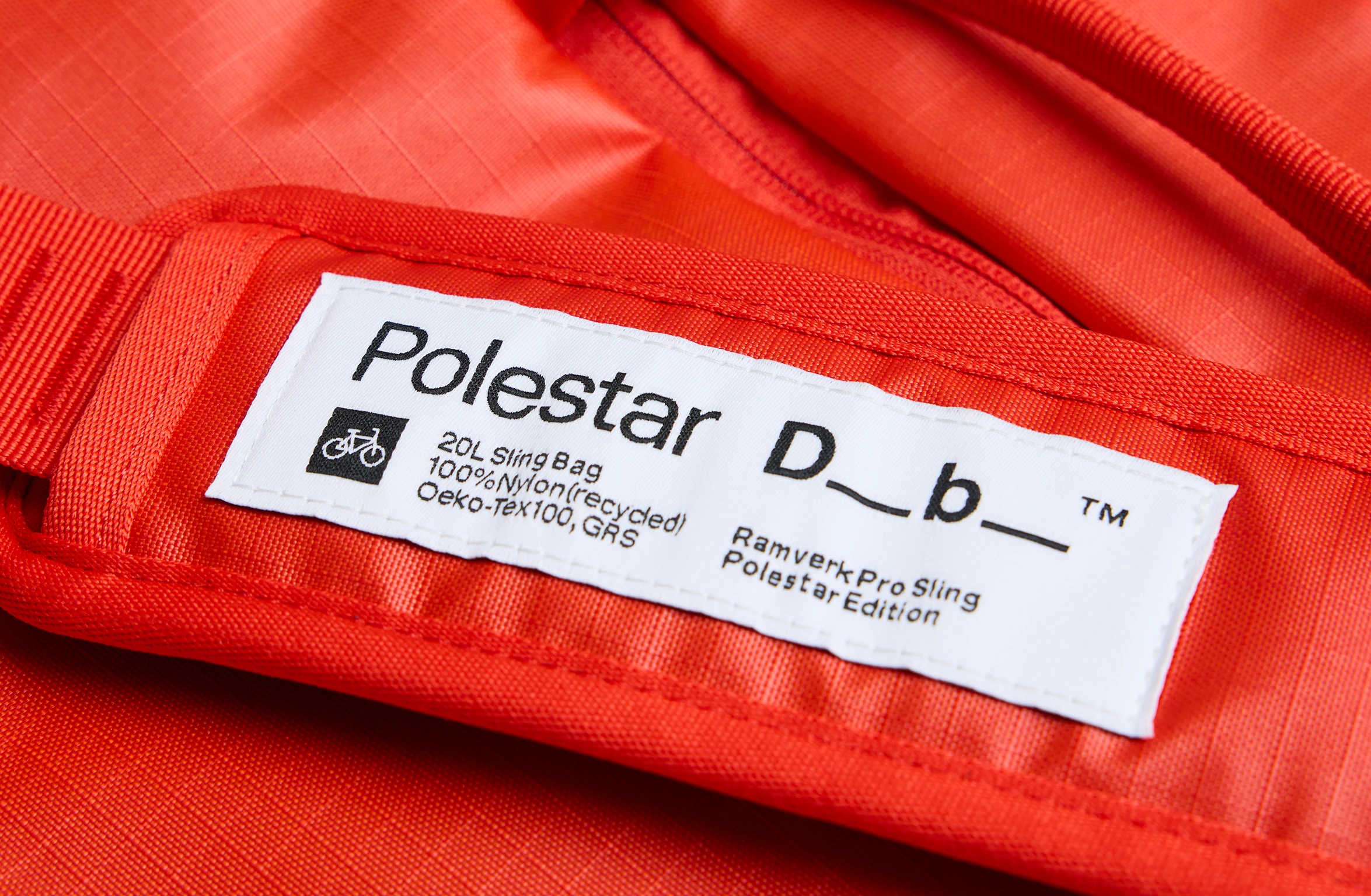 Red sling bag with an adjustable strap and a branded label on the shoulder pad.