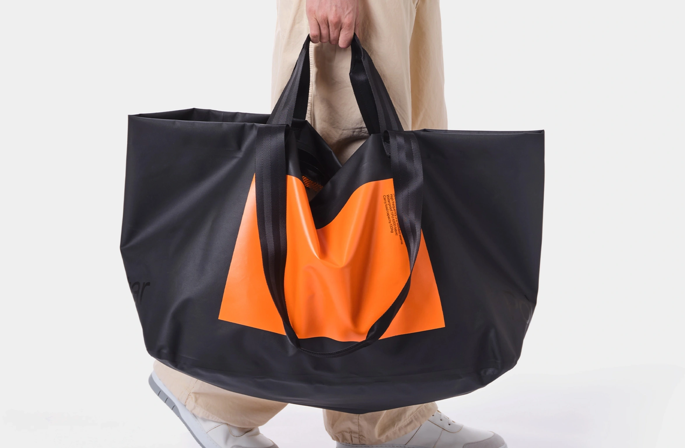 Wasserdichte offene Tragetasche in Schwarz mit großem Rechteck in Orange und kleinem Polestar Schriftzug vorn