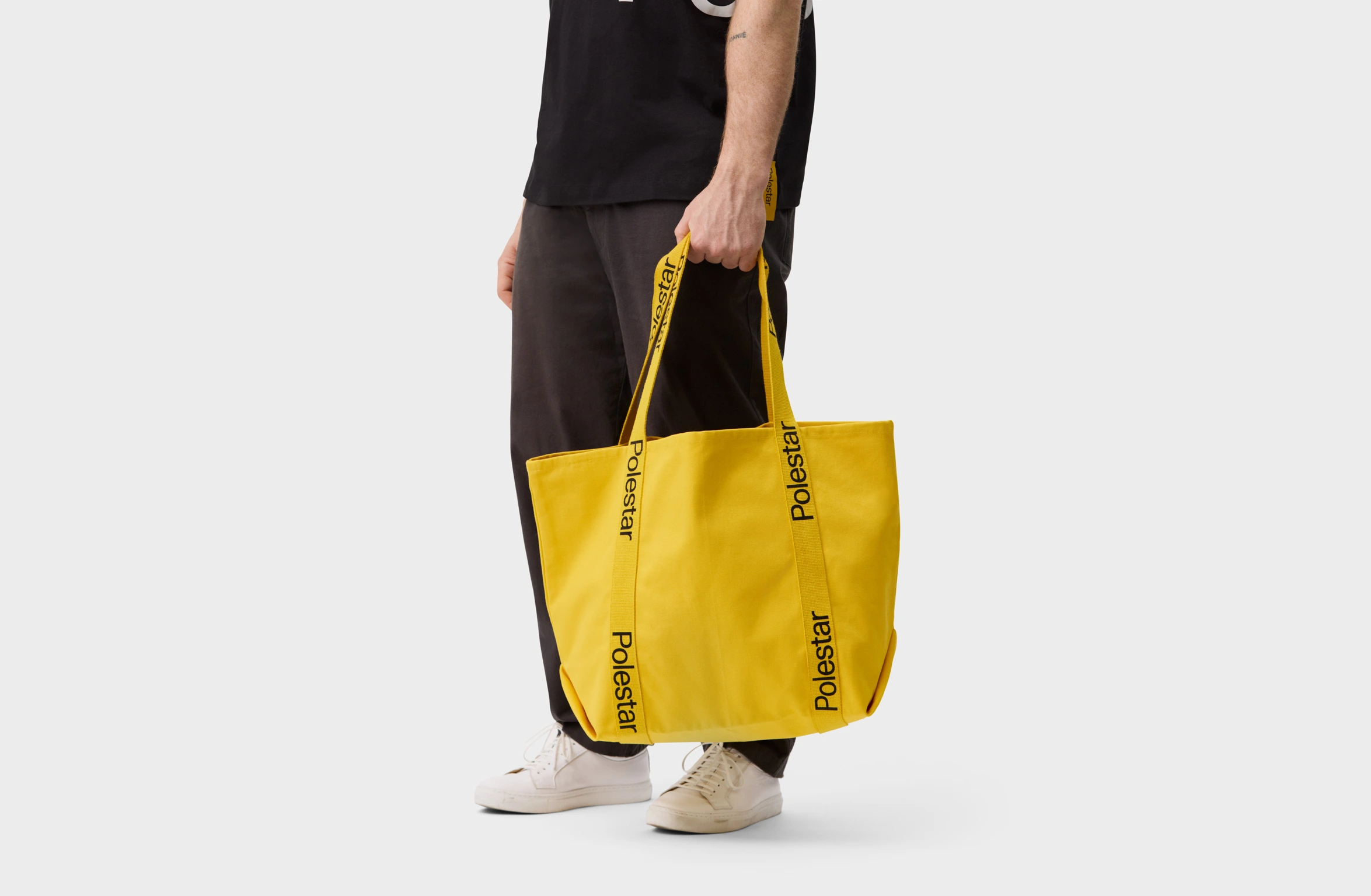 Yellow tote bag with handles adorned with a black Polestar wordmark