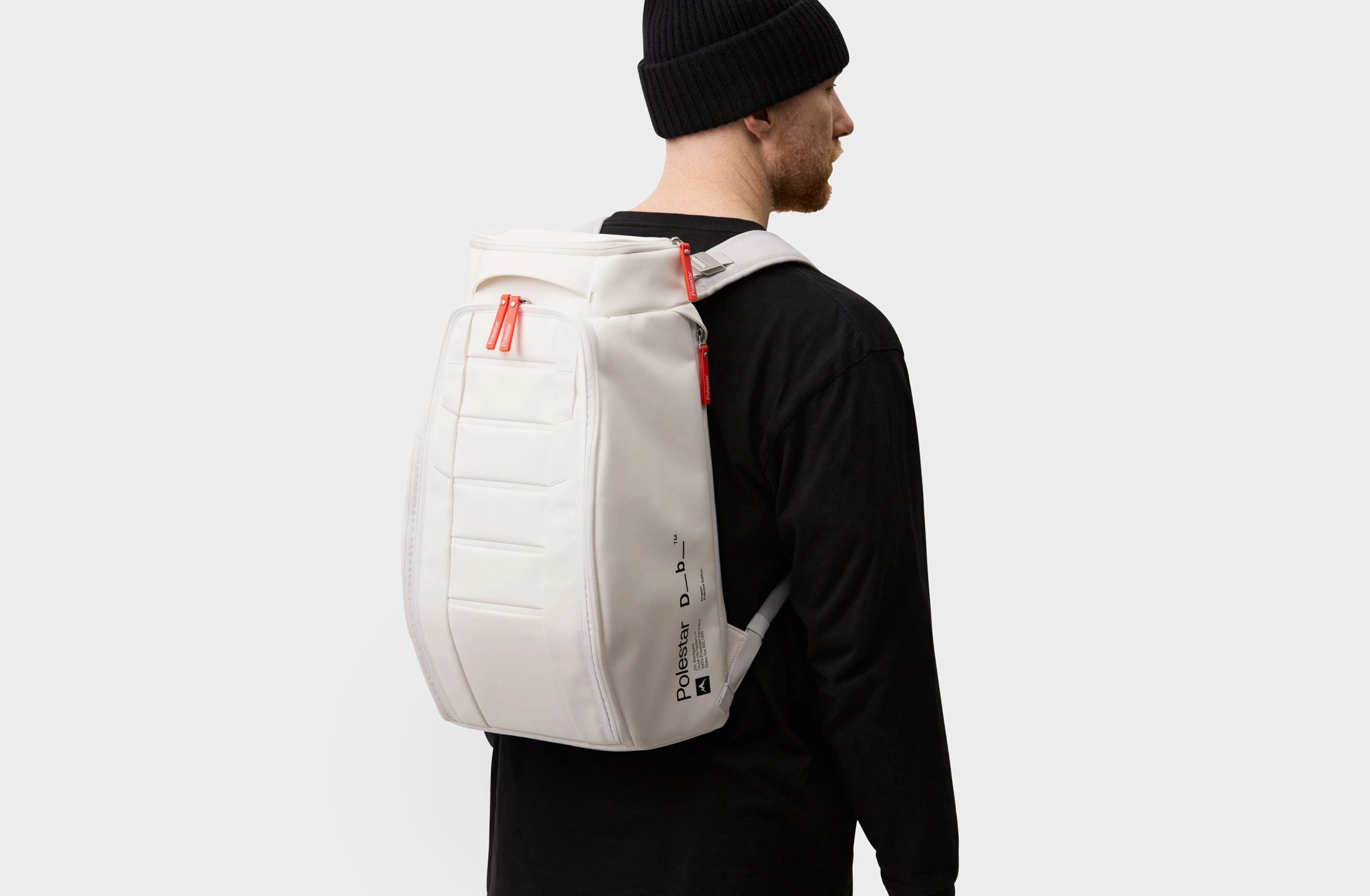 White backpack with orange details, padded straps and Polestar × Db branding on the side.