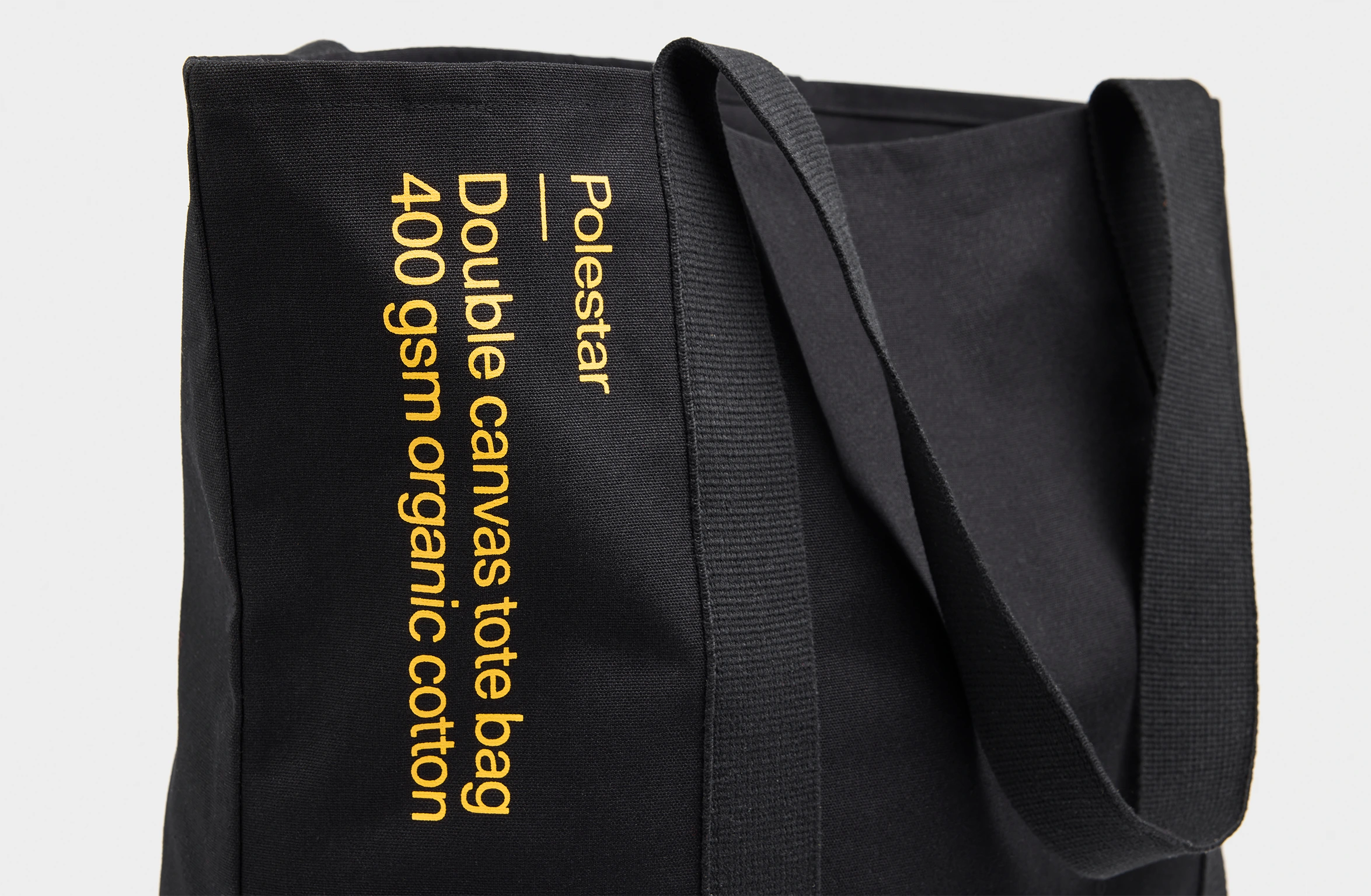 Black tote bag with a small yellow Polestar wordmark