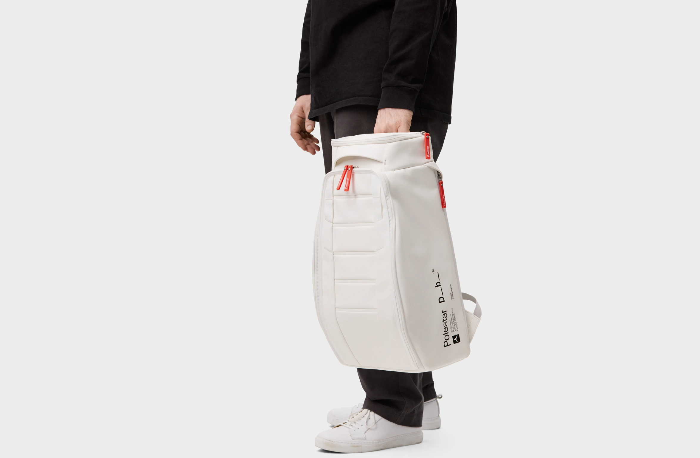 Witte rugzak met oranje details, gewatteerde schouderbanden en Polestar × Db-logo aan de zijkant.