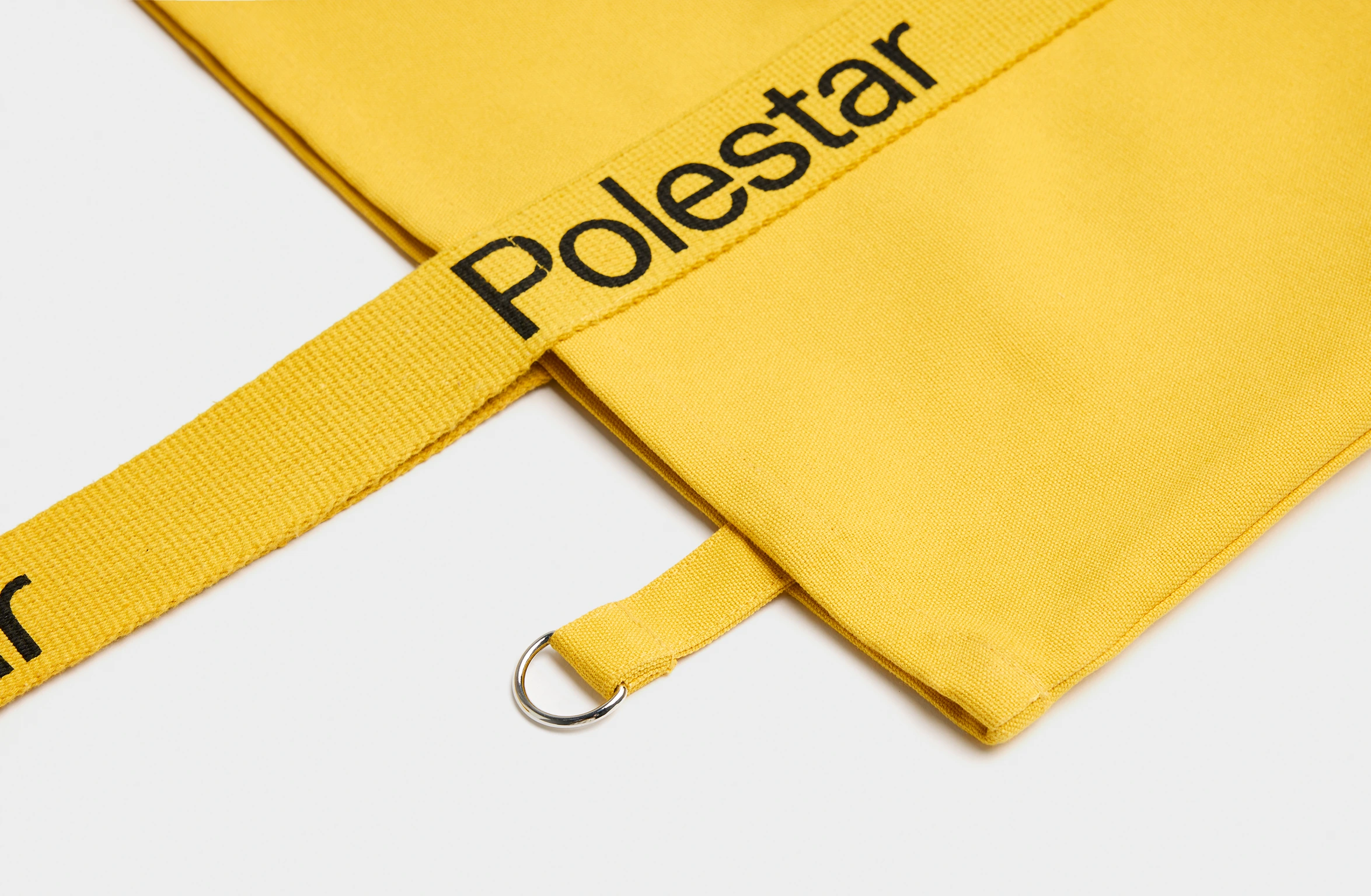 Gul tygväska med handtag dekorerade med ett svart Polestar-ordmärke