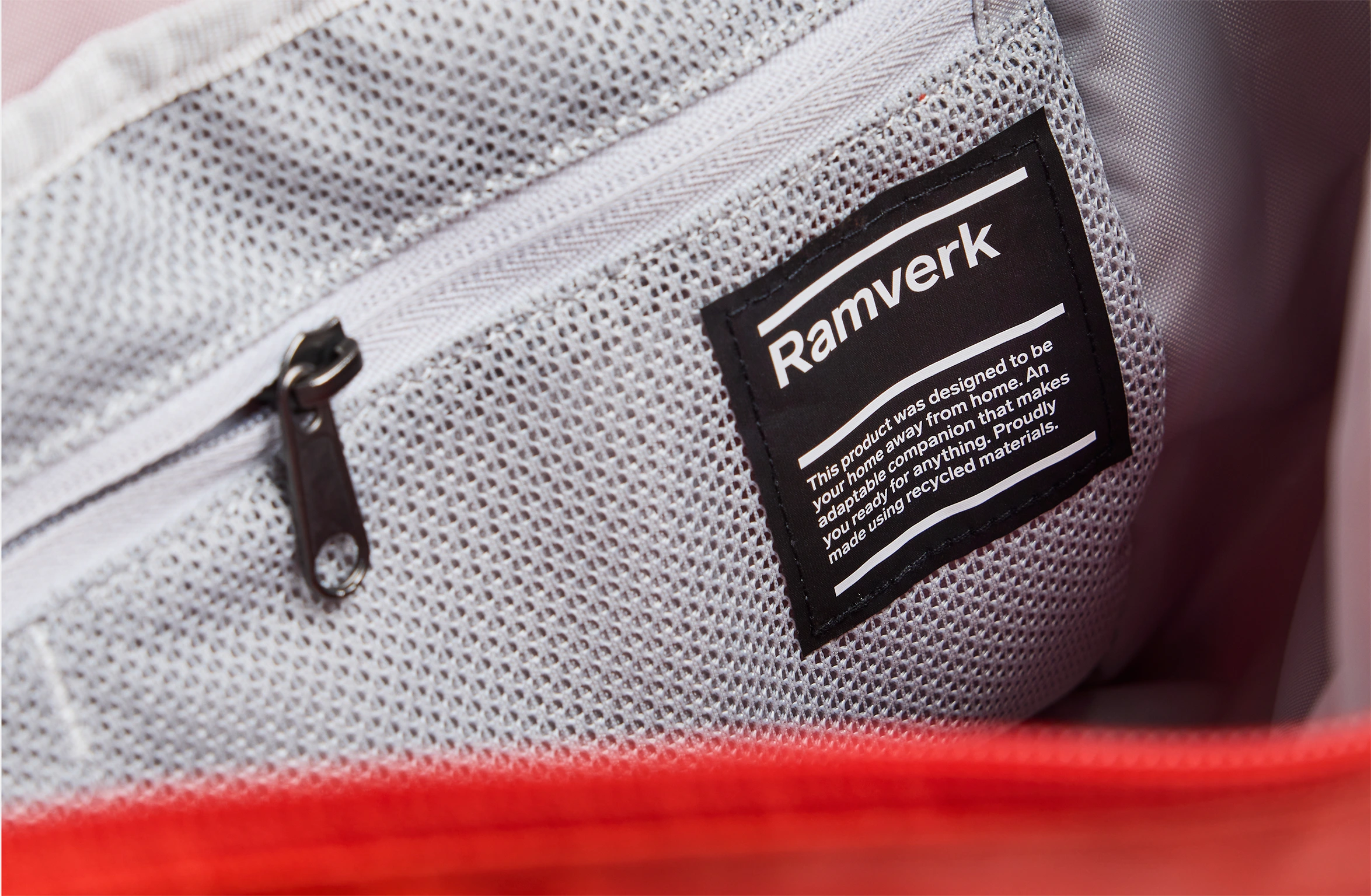 Red sling bag with an adjustable strap and a branded label on the shoulder pad.