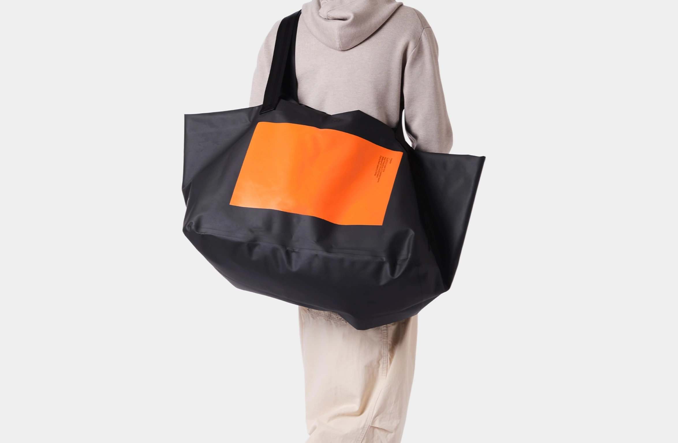Svart, vanntett, åpen tøyveske med stort, oransje, rektangulært design og et lite Polestar-ordmerke på forsiden