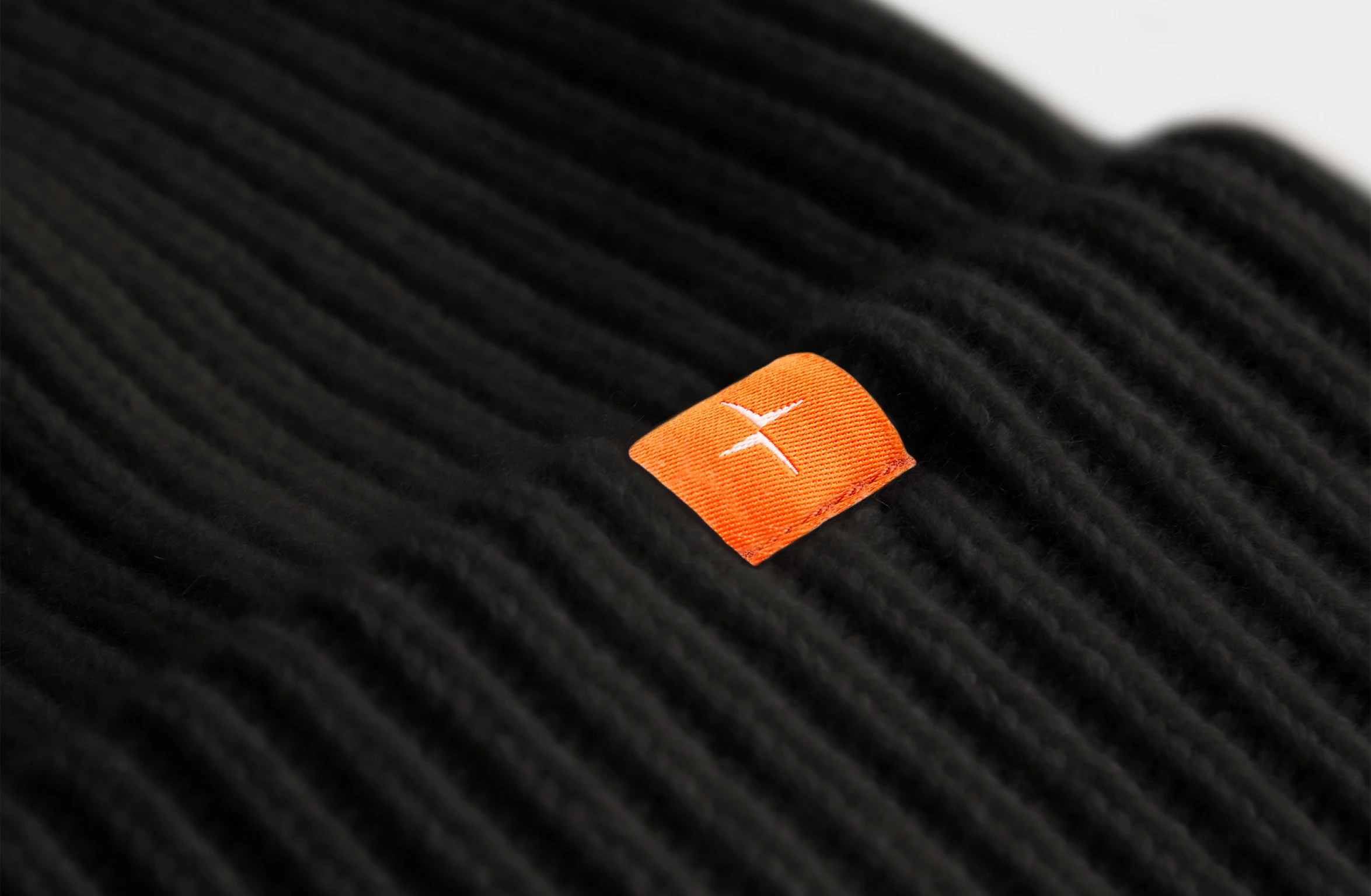 Sort strikket kashmirhue med en lille orange Polestar-detalje