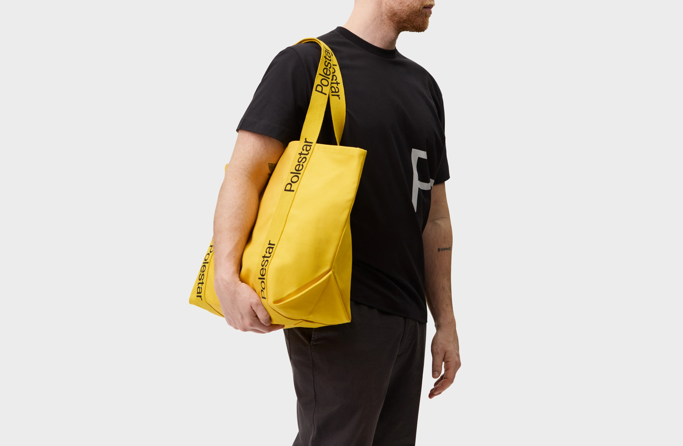Yellow tote bag with handles adorned with a black Polestar wordmark
