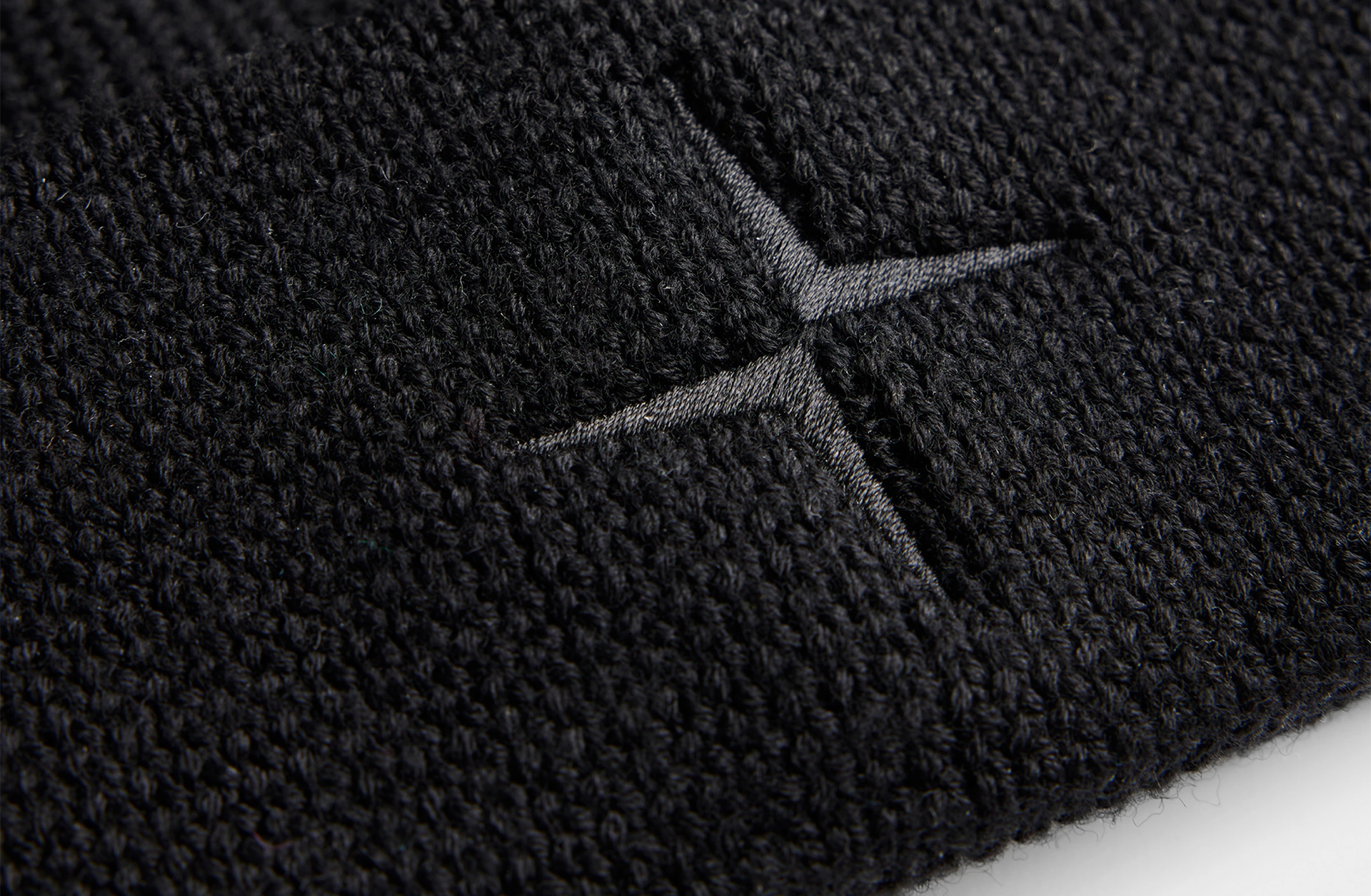 Sort hue i ribbet uld med sort broderet Polestar-symbol på forsiden