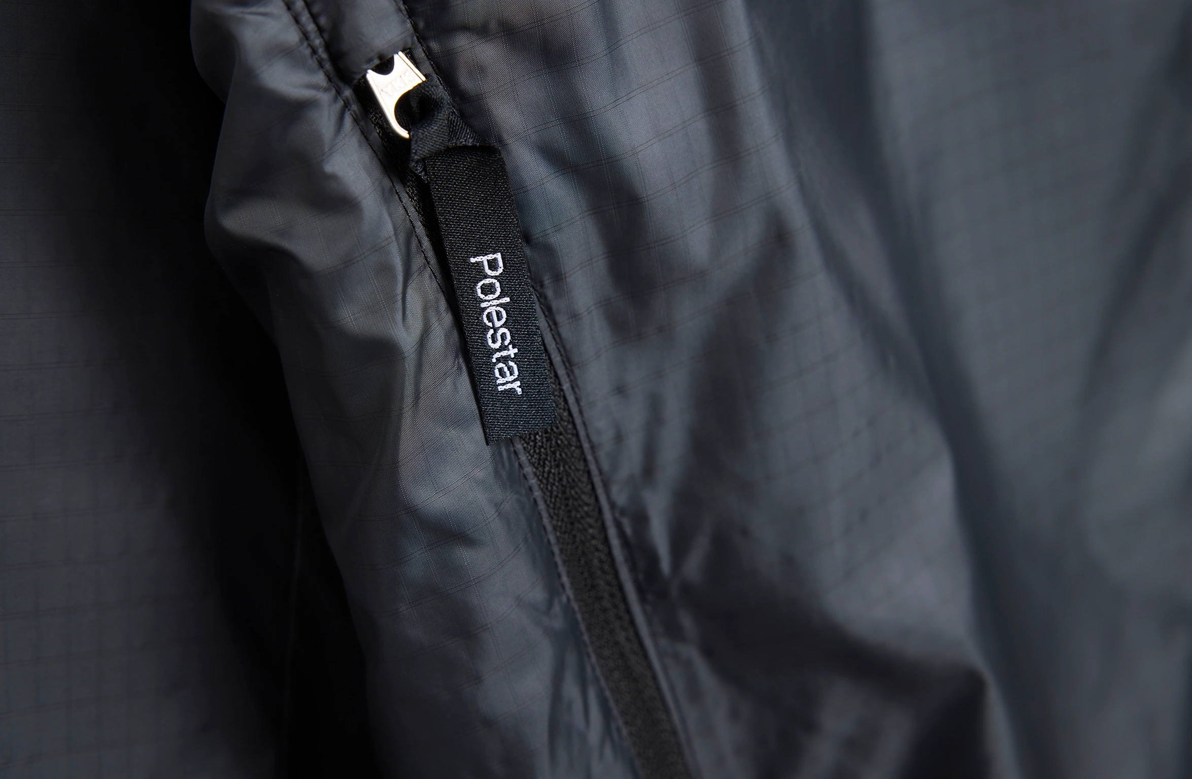 Black lightweight jacket with hood, full zipper, and discreet Polestar wordmark