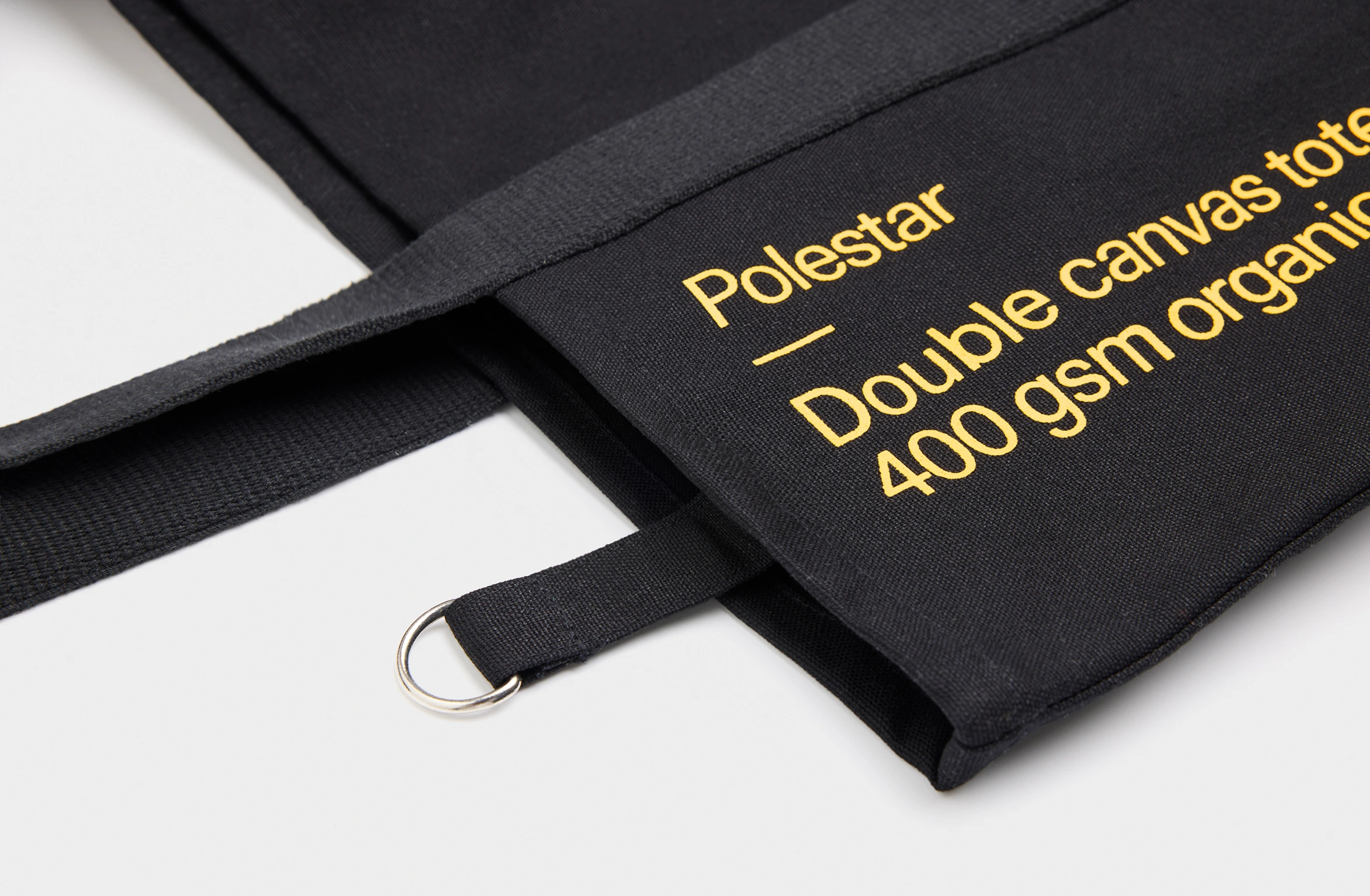 Black tote bag with a small yellow Polestar wordmark
