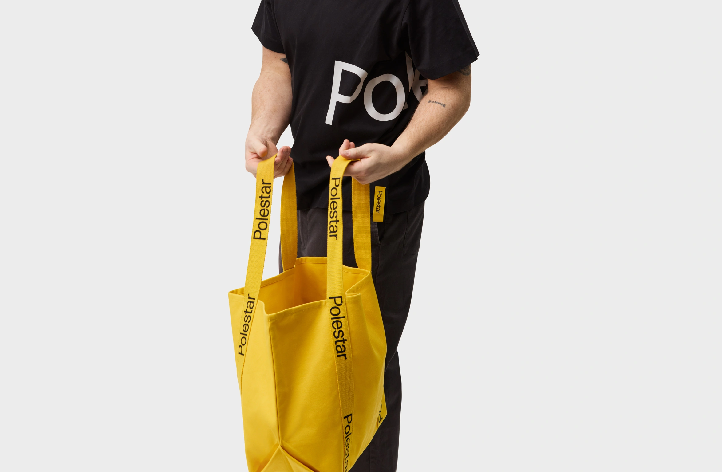 Yellow tote bag with handles adorned with a black Polestar wordmark