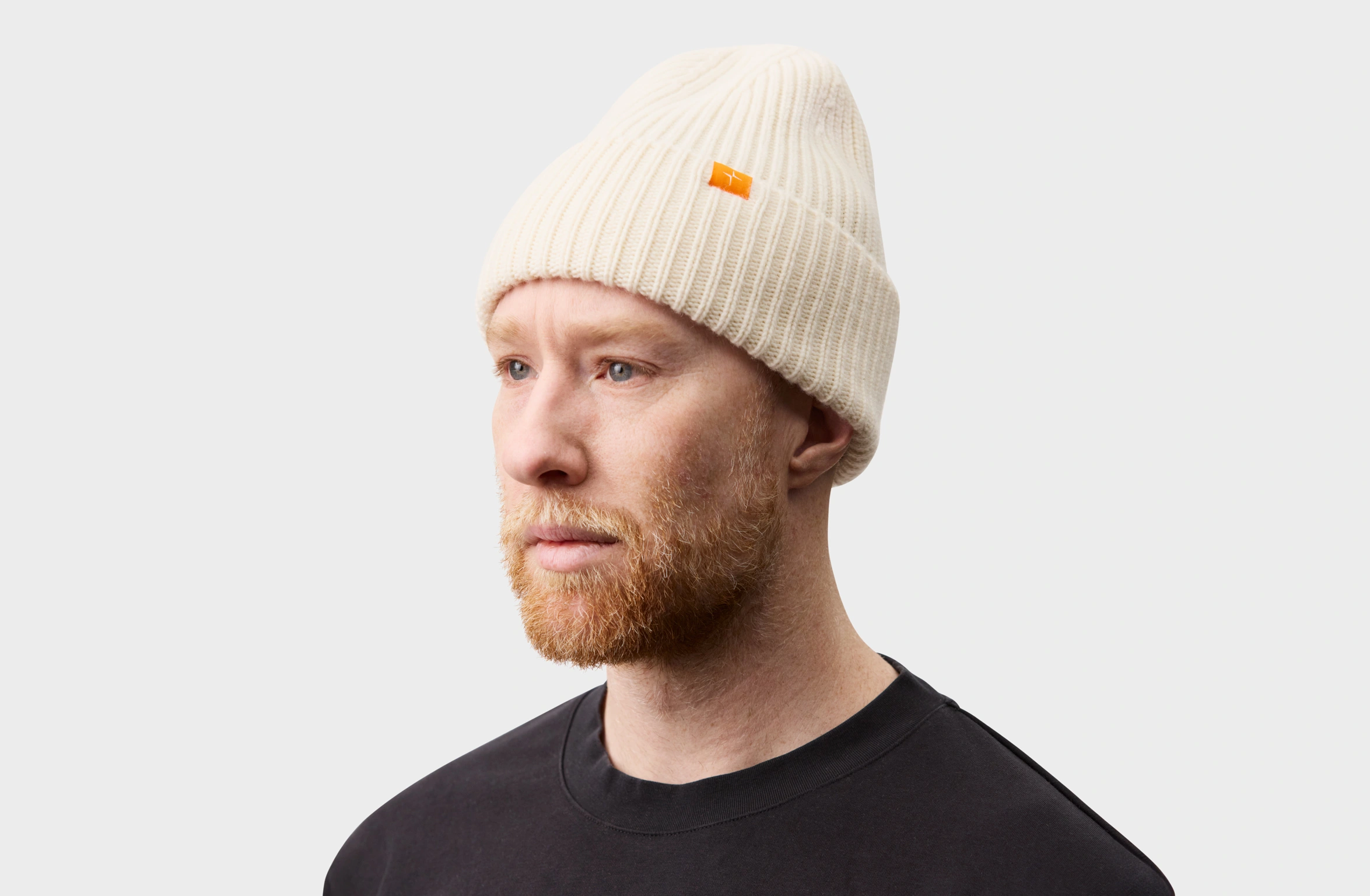 Beige knitted cashmere beanie with a small orange Polestar detail