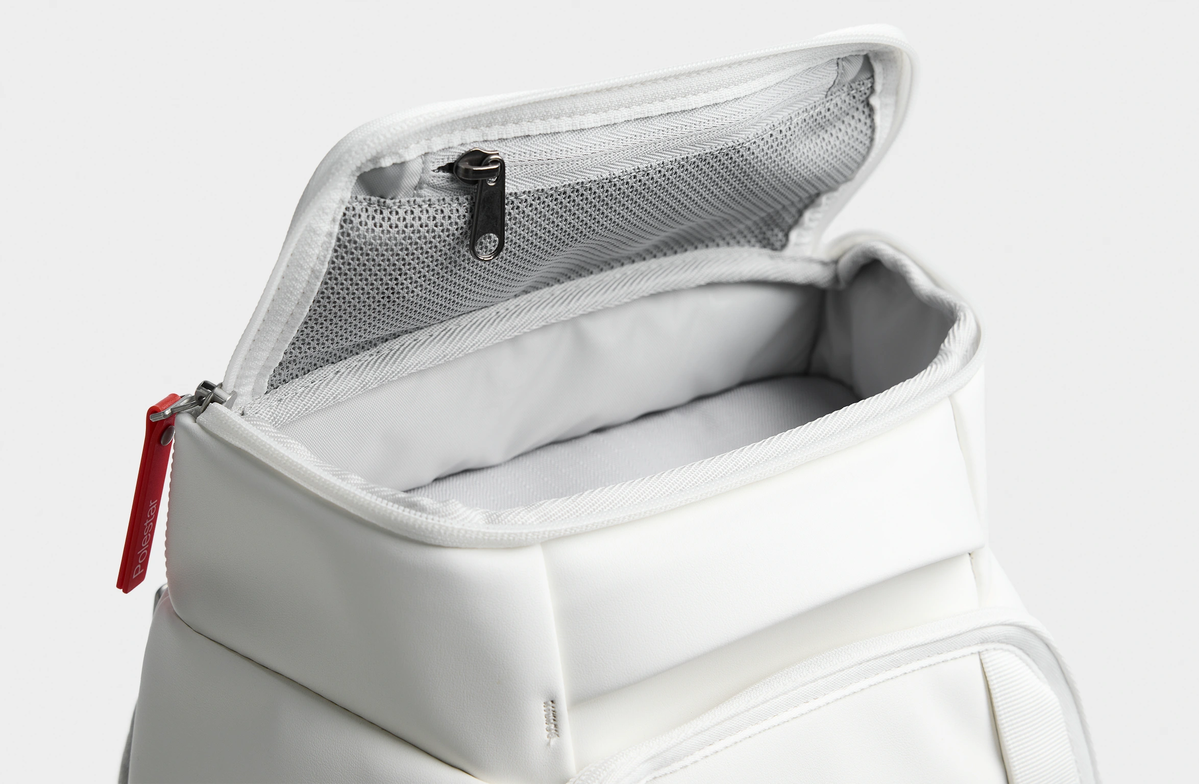 White backpack with orange details, padded straps and Polestar × Db branding on the side.