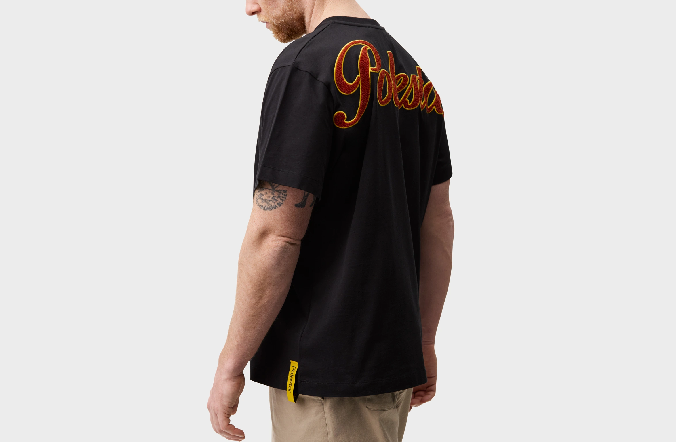 Schwarzes T-Shirt mit markantem Polestar Plüsch-Schriftzug in Rot und Gelb am oberen Rücken