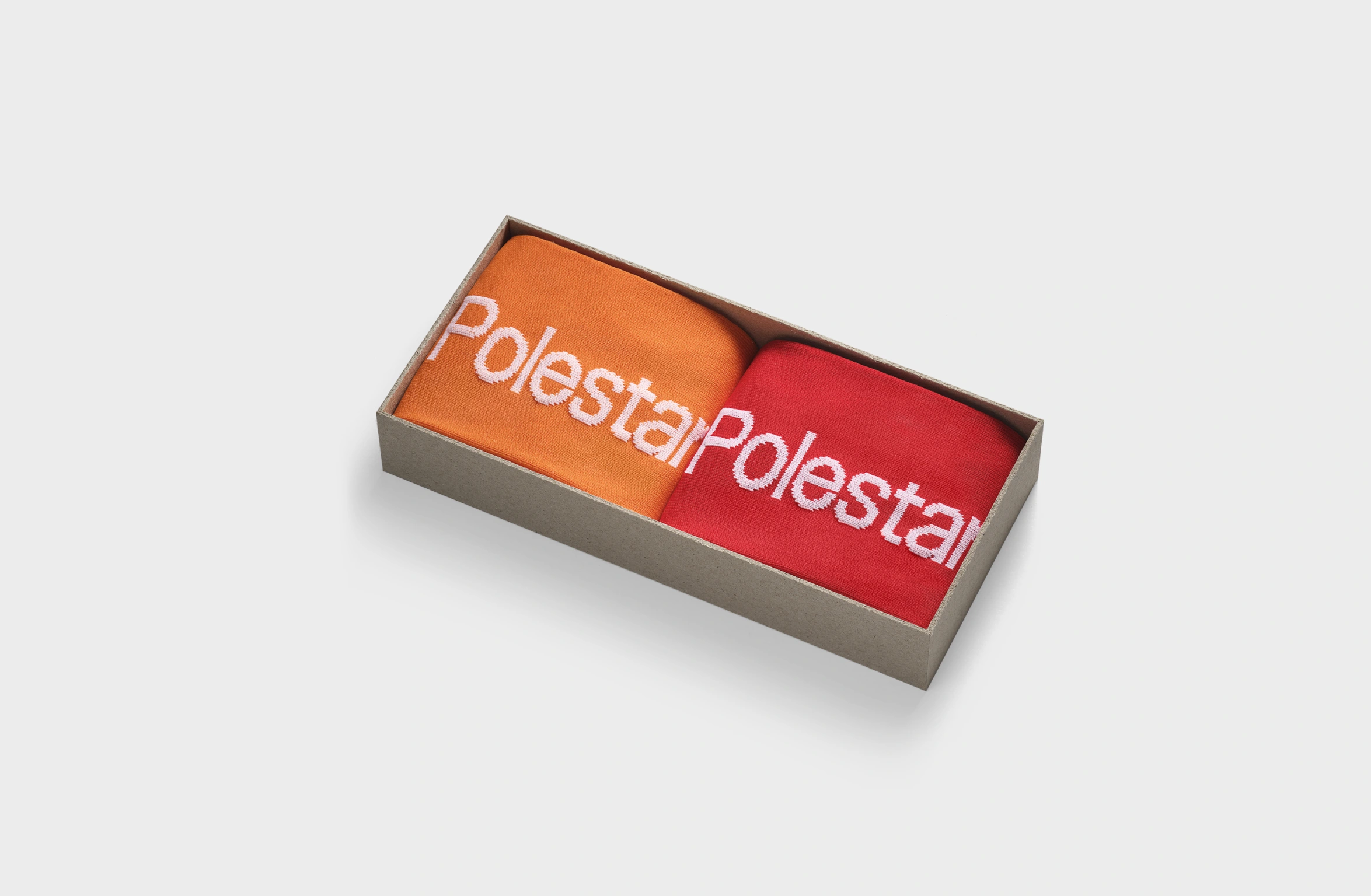 Pakke med sokker med Polestar-ordmerke. En i oransje og en i rød.