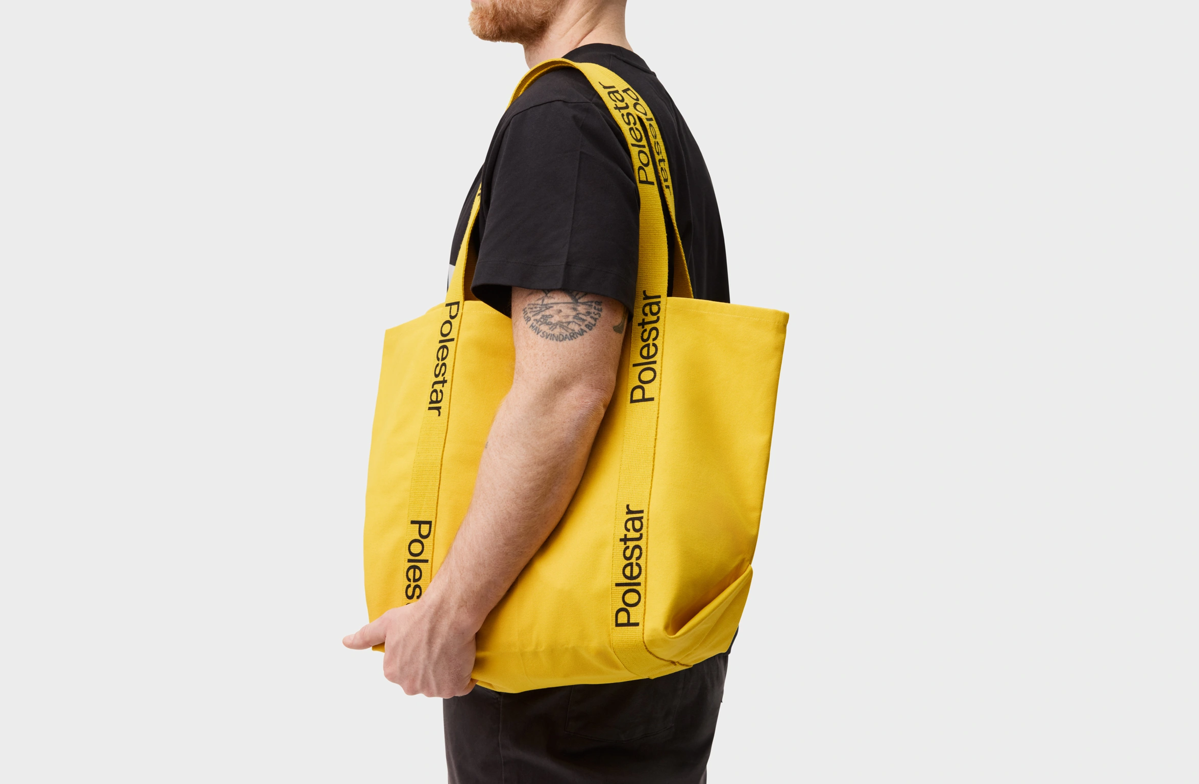 Yellow tote bag with handles adorned with a black Polestar wordmark