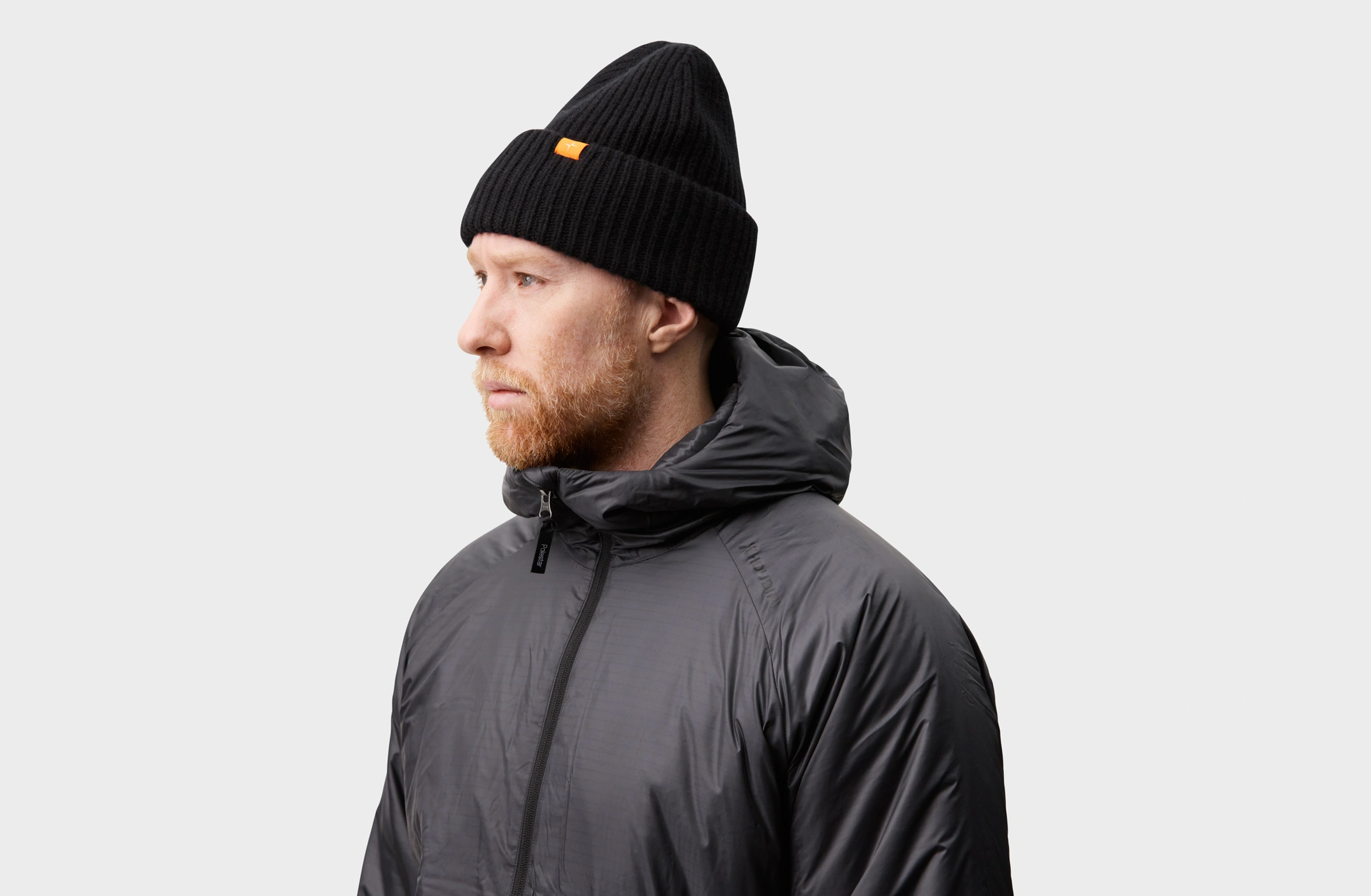 Zwarte gebreide kasjmier beanie met een klein oranje Polestar-label