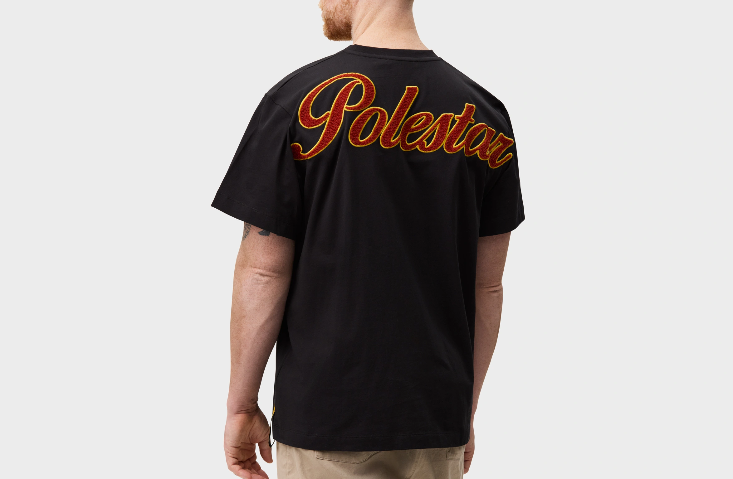 Black t-shirt with a lagre bold teddy Polestar wordmark in red and yellow across the upper back